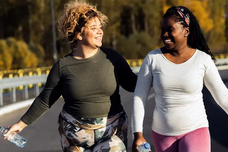 Two happy female friends jogging on road