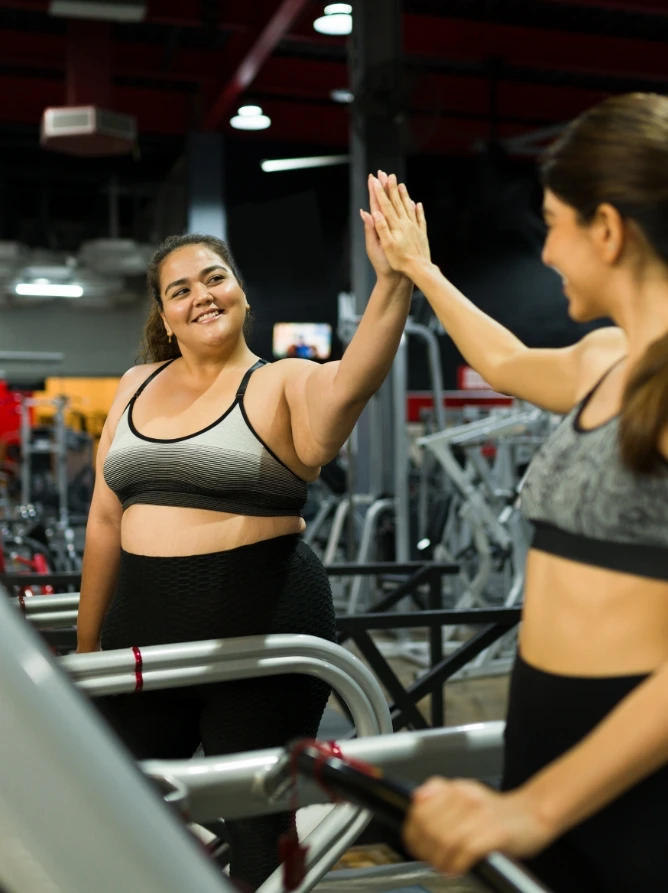 Overweight woman in gym looking in mirror at slimmer self