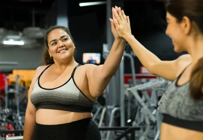 Overweight woman in gym looking in mirror at slimmer self