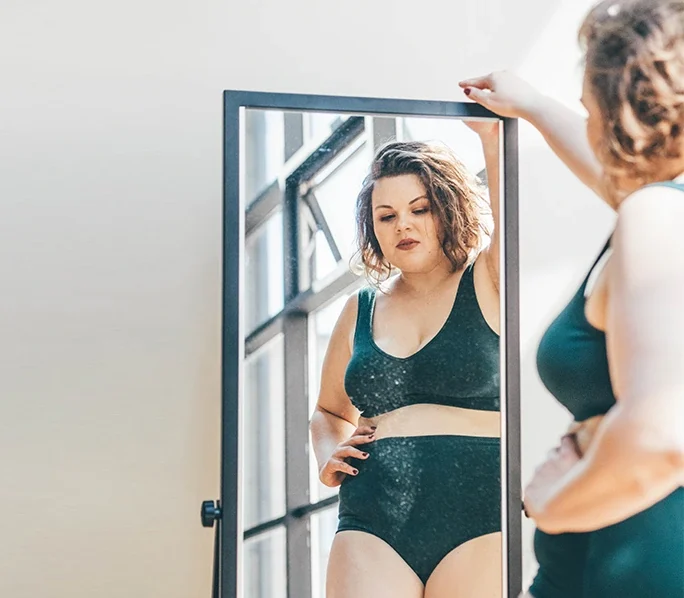 Plus size woman looking at reflection in the mirror