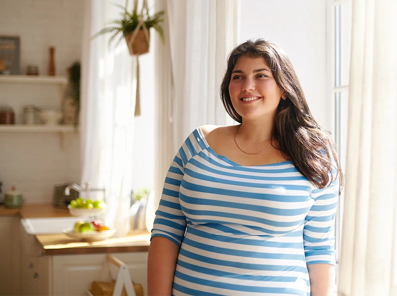 Overweight woman smiling in kitchen with blue stripe shirt