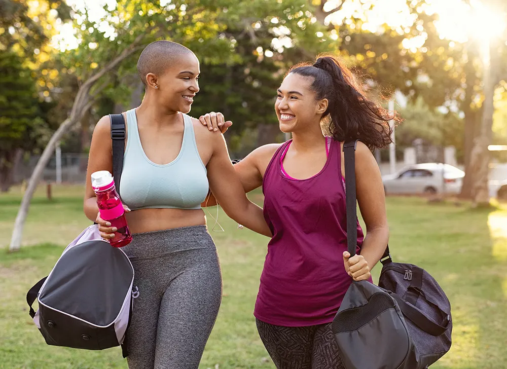 Two women walking with duffle bags after workout