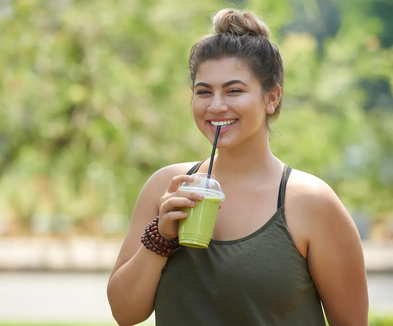 Young plus size woman smiling while drinking green smoothie