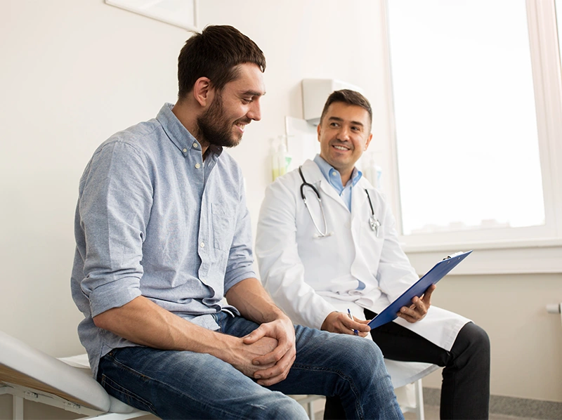 Doctor with clipboard showing male patient in hospital