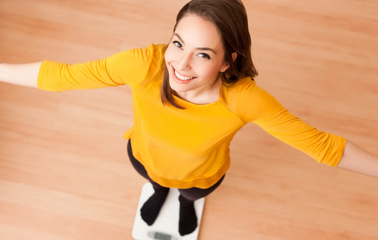 Young healthy woman standing on the scale after combatting Type 2 diabetes