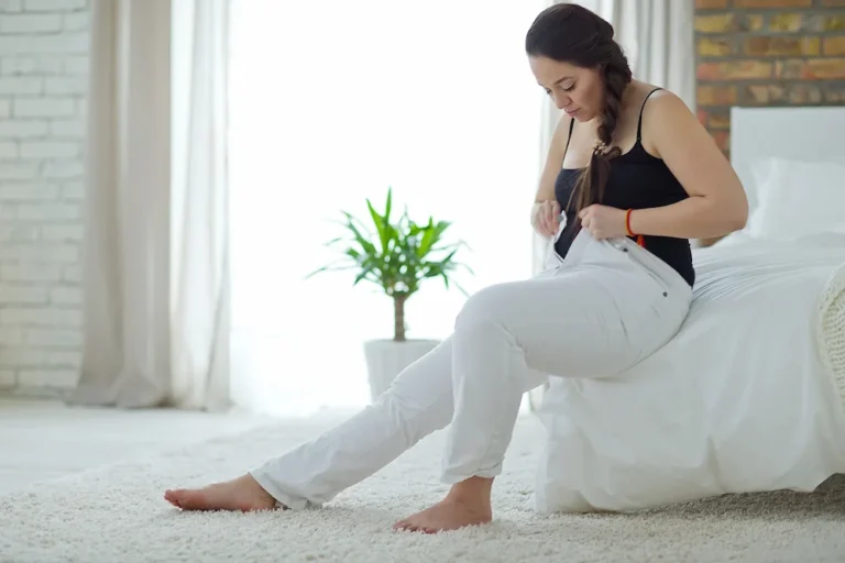 Woman sitting down attempting to put on pants