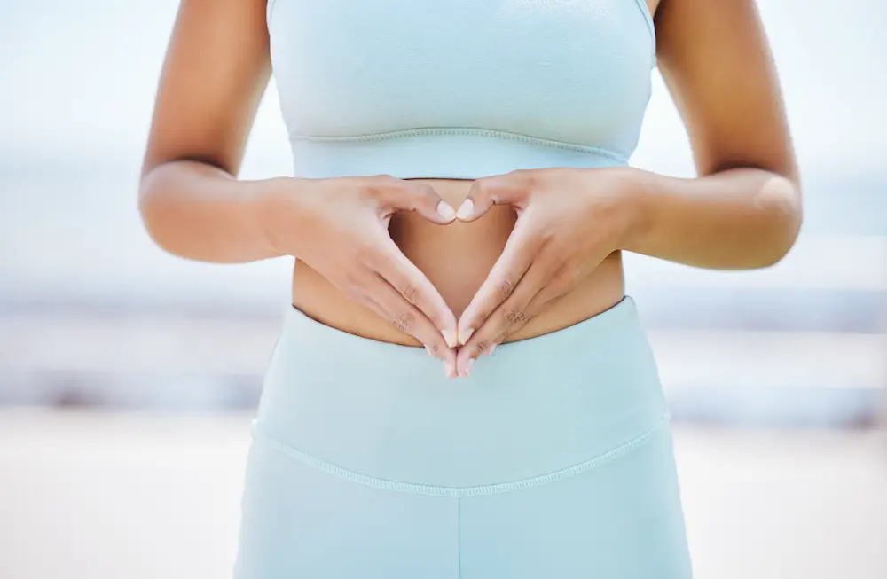 woman making a heart shape with her hands over her stomach