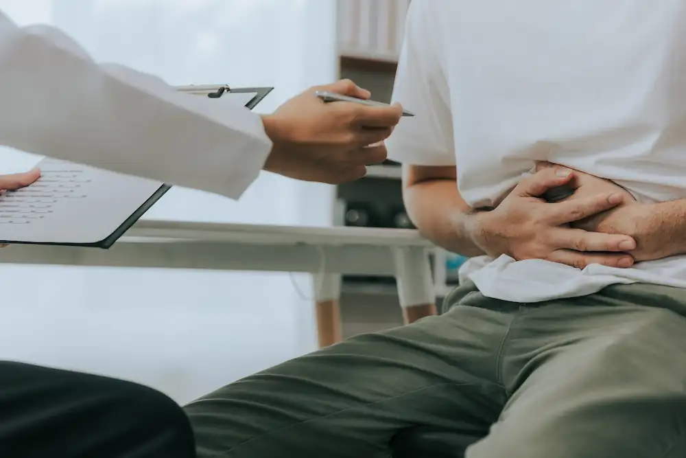 middle aged man holding his stomach at the doctors office