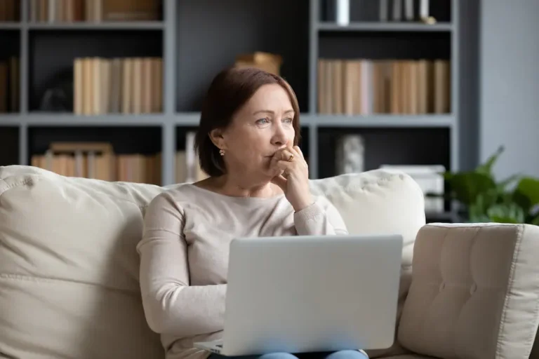 pondering woman sitting on couch with laptop