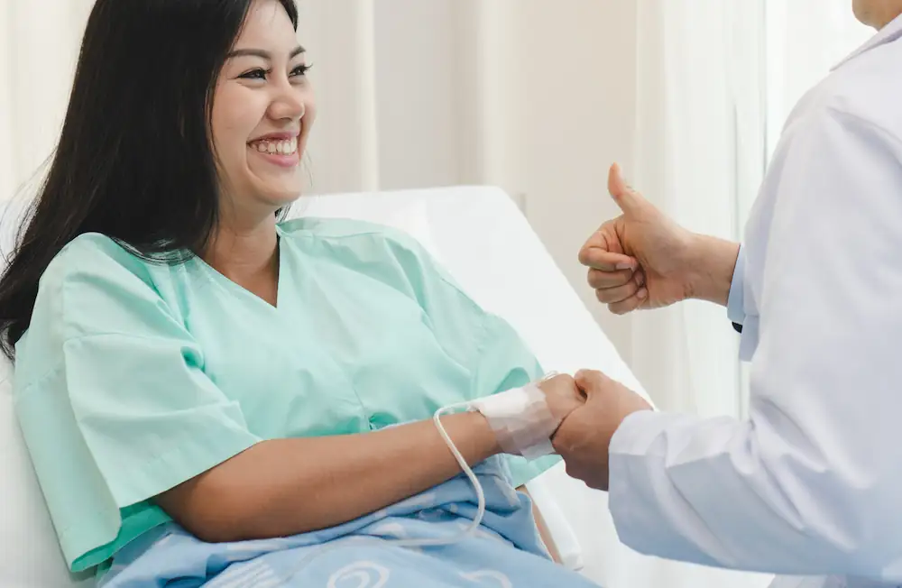 woman recovering after surgery and doctor giving a thumbs up